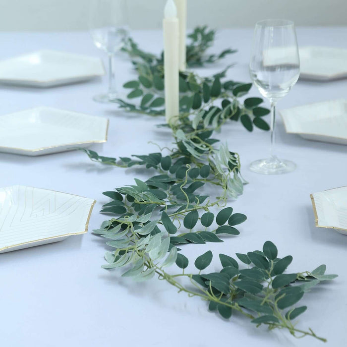 Elegant table setting with greenery and white plates for a sophisticated dining experience.