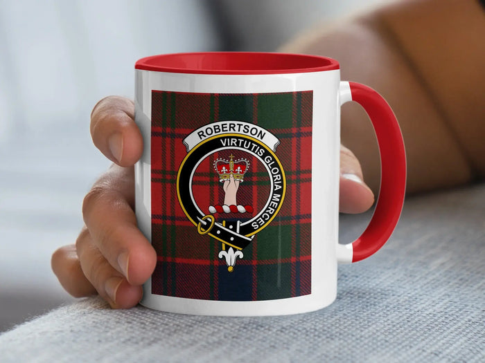 Red-accent Robertson crest mug held in a hand, with a tartan background.