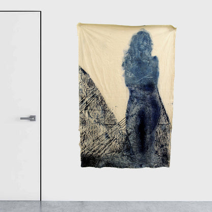 The artwork 'Crepuscular' by Johanna Ryan features a striking silhouette rendered in deep indigo cyanotype on coffee-stained canvas. Abstract textural patterns create a moody landscape effect beneath the ethereal figure. The 70x49 inch piece combines traditional photographic processes with mixed media elements, resulting in a dreamlike composition of blue tones against warm sepia background.