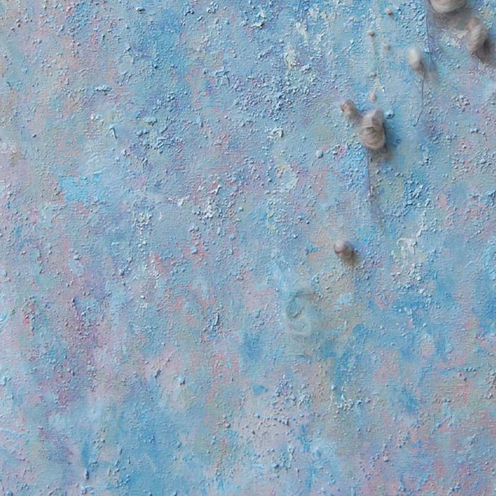 The artwork 'Eruption' by Noriko Okada features a textured abstract composition with ethereal blue and pink hues blending across the canvas. Raised circular elements create a dimensional effect, while yarn details add organic texture. The surface resembles a celestial landscape with its dreamy pastel color palette and tactile, crater-like formations.