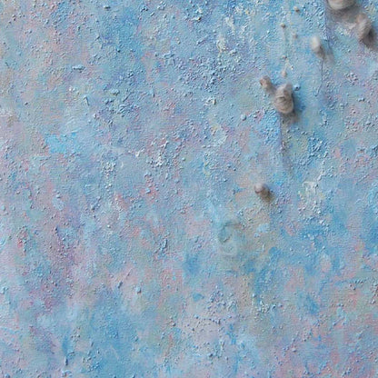 The artwork 'Eruption' by Noriko Okada features a textured abstract composition with ethereal blue and pink hues blending across the canvas. Raised circular elements create a dimensional effect, while yarn details add organic texture. The surface resembles a celestial landscape with its dreamy pastel color palette and tactile, crater-like formations.