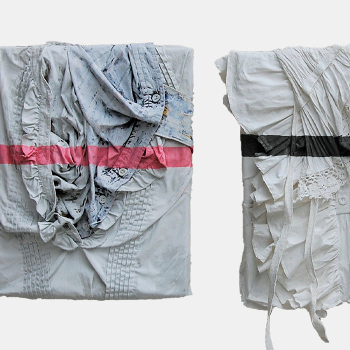The artwork 'Family' by Noriko Okada features two abstract textile compositions side by side. Each piece showcases crumpled and pleated fabric in pale gray tones, with one adorned by a striking pink horizontal stripe and the other with a black band. The textured surfaces create dramatic shadows and folds, emphasizing the sculptural qualities of the oil-painted fabric.