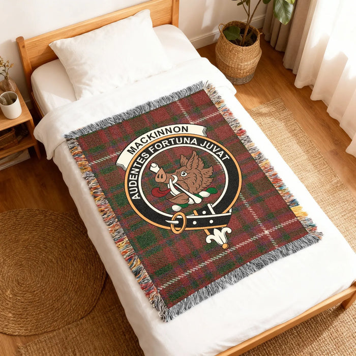 Angled view of MacKinnon boar-crest woven blanket on a wooden bed