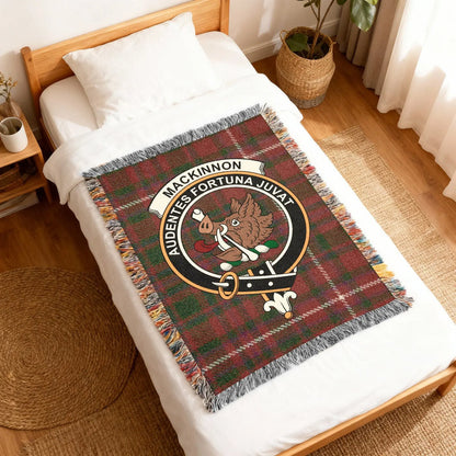 Angled view of MacKinnon boar-crest woven blanket on a wooden bed