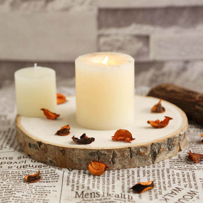 Candle on a wooden slice with dried petals on newspaper background.