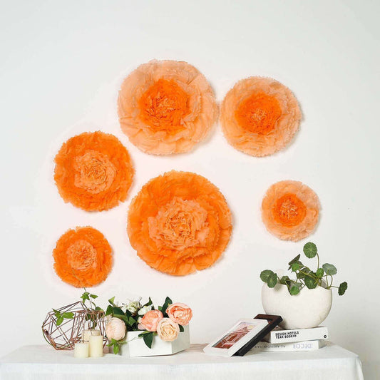Orange tissue paper flowers on a wall with decorative plants and a photo display.