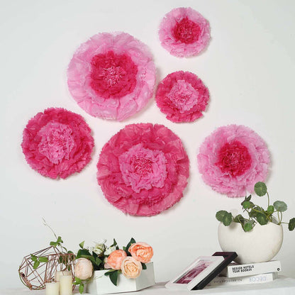 Pink tissue paper flowers arranged on a wall with decorative plants and objects.