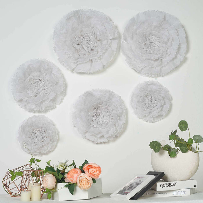 Decorative white paper flowers on a wall with plants and books in the foreground.