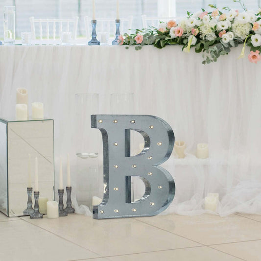 Decorative marquee letter "B" with lights at a wedding setup.
