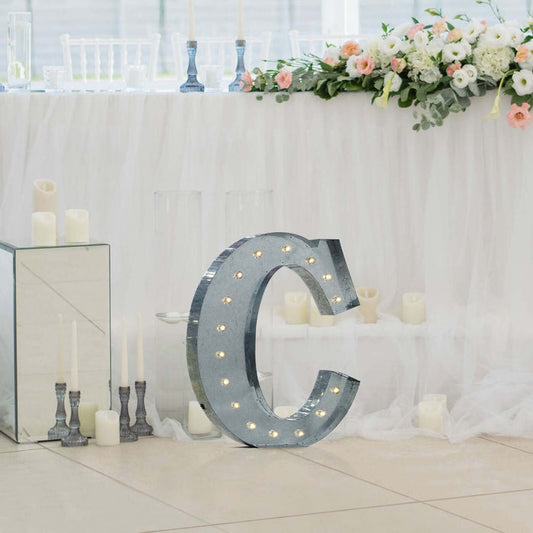 Decorative marquee letter "C" illuminated with lights at an elegant event setting.
