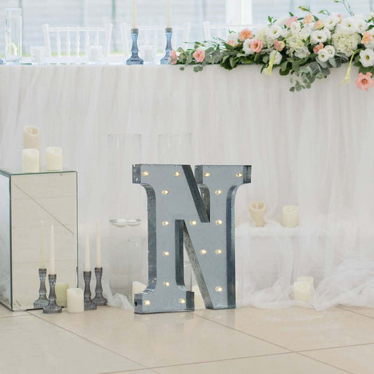 Decorative marquee letter "N" with lights at a wedding setting.