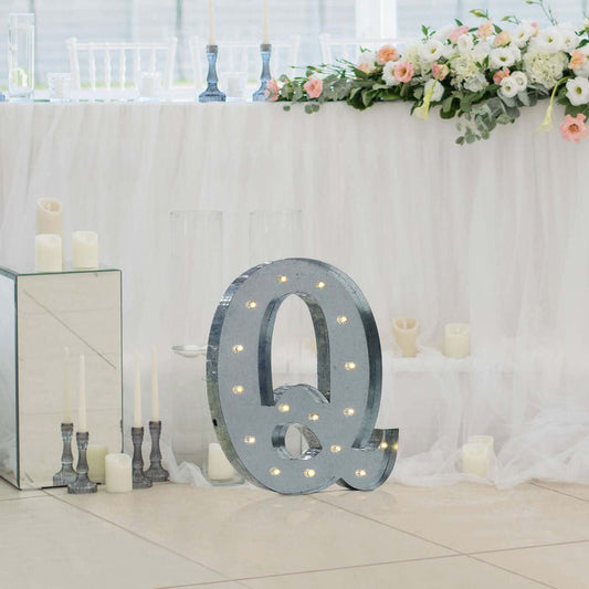 Decorative marquee letter "Q" with lights at an event table setting.