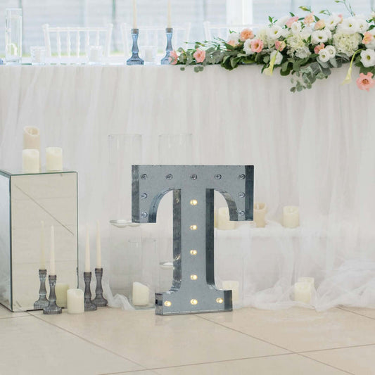 Marquee letter "T" with lights, displayed at a wedding venue.