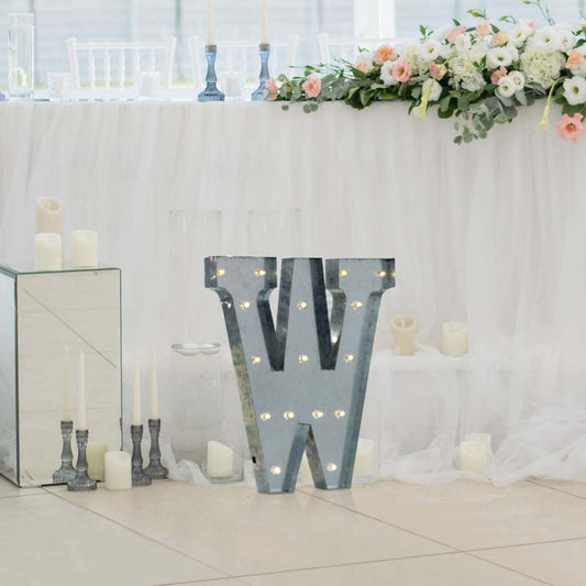 Marquee letter 'W' with lights at a decorated wedding venue.