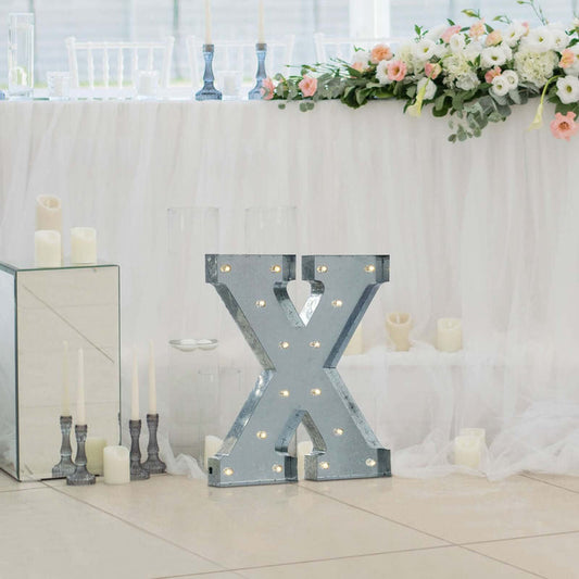 Decorative marquee letter "X" with lights at a wedding reception.